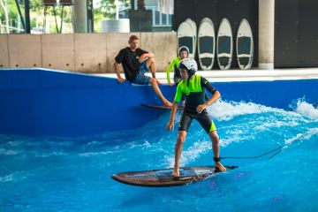 EIn Kind mit Helm surft auf der Indoorwelle in der Jochen Schweizer Arena